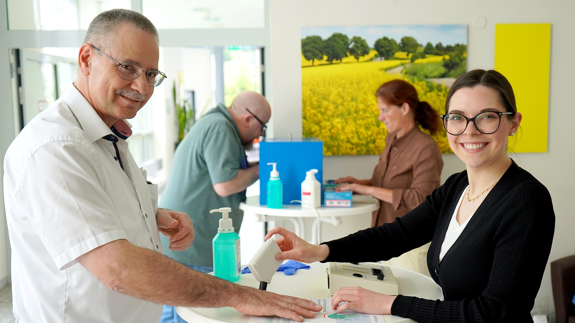 Dr. Wes Nakchbandi lässt hier von Außendienstmitarbeiterin Sabrina Burkhardt seine Haut prüfen. Im Hintergrund sind Edgar Rützel vom Sozialdienst und die Leitende Pflegekraft Astrid Brust an einem Schwarzlichtkasten zu sehen.