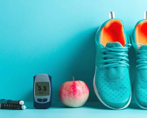 Diabetes-Messgerät, Apfel und ein paar blaue Schuhe.