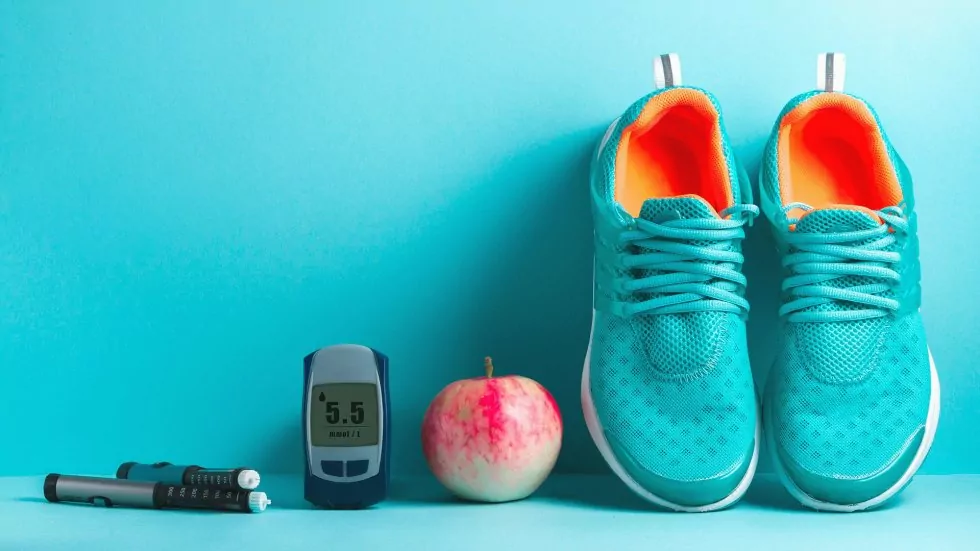 Diabetes-Messgerät, Apfel und ein paar blaue Schuhe.