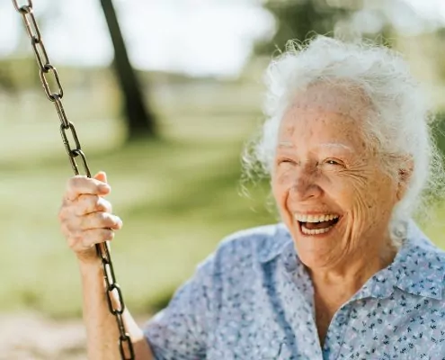 Ältere Frau in einem hohen Alter die lachend schaukelt.