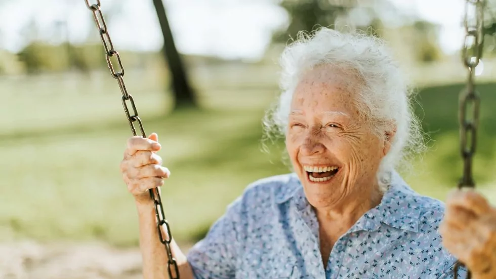 Ältere Frau in einem hohen Alter die lachend schaukelt.