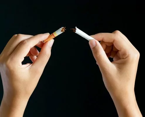 Zwei Hände die eine Zigarette zerbrechen um mit dem Rauchen aufzuhören.